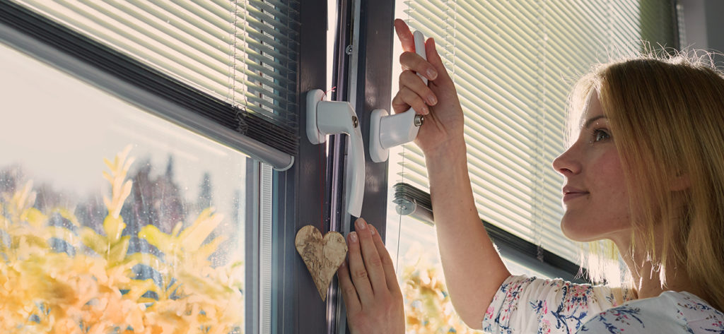 Frau schliesst Fenster mit Sicherheitsgriff.