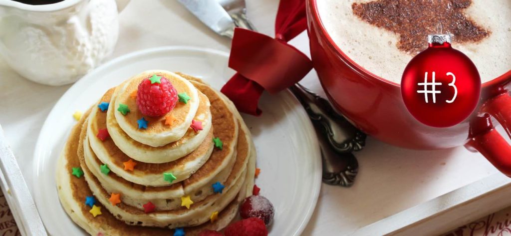 Neben einem Cappuccino bilden Verschieden grosse Pancakes einen Weihnachtsbaum.