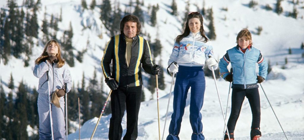 Familie mit zwei Kindern im Outfit der 70er-Jahre beim Skifahren