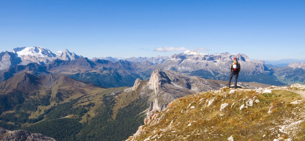 Wanderer steht auf einem Berg und schaut zu den Berggipfeln.